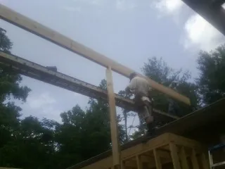 Carpenter setting a ridge beam over a new addition frame — Ice Dam Removal by Roofing Brothers in Brooklyn
